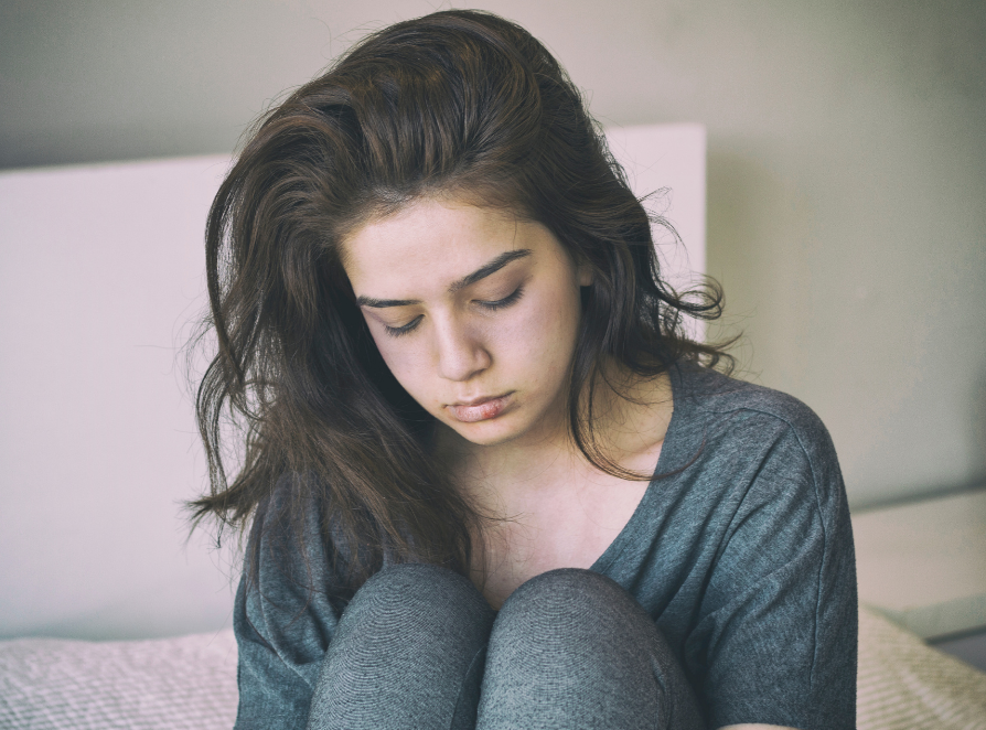 A young woman looks down in shame